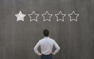 Hombre de espaldas, mirando una pizarra con estrellas de valoración, solo una es positiva