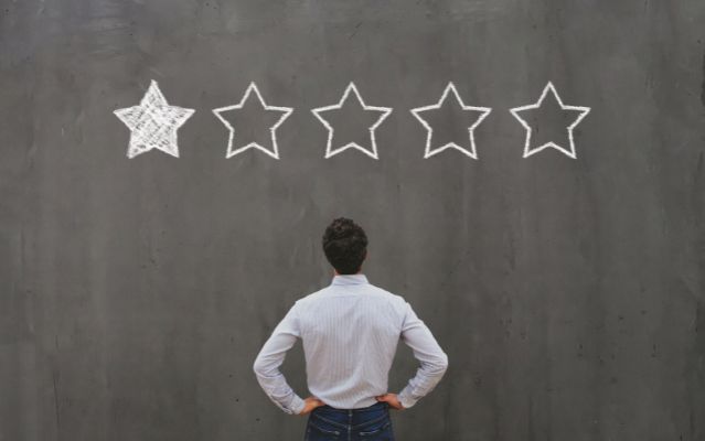 Hombre de espaldas, mirando una pizarra con estrellas de valoración, solo una es positiva